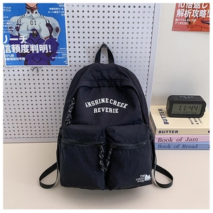 Detail of black multi-pocket school backpack with white letter print on a desk