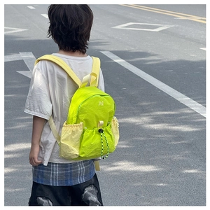 Detail of child wearing a vibrant neon green drawstring backpack for outdoor activities