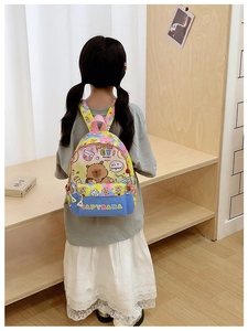 Kid wearing cartoon Capybara backpack with colorful gradient print in cozy home setting