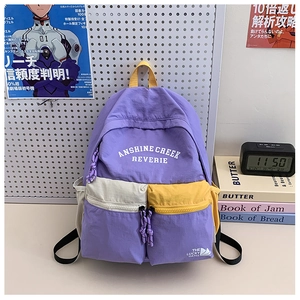 Close-up of a purple school backpack with contrast yellow straps and printed lettering
