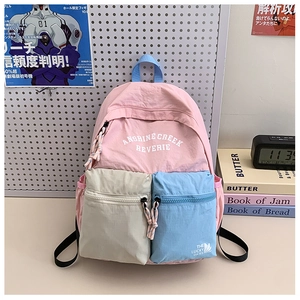 Close-up of pink school backpack with light grey and blue pockets and letter print