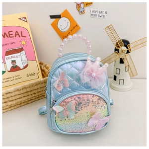 Detail of blue quilted mini backpack featuring pearl handle and lace crown decoration