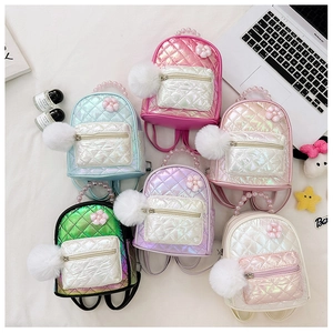 Macro detail of quilted iridescent mini backpacks with pearl handle and pompom charm