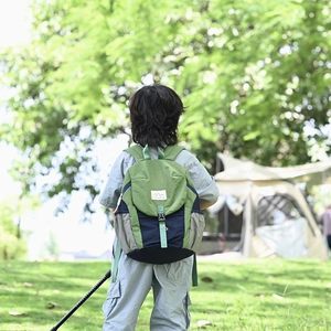 Vue extérieure d'un sac à dos enfant bicolore avec logo Mountains dans un parc verdoyant