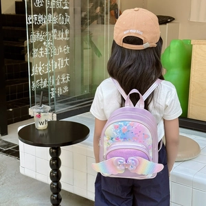 Cute purple sequin backpack for kids with rainbow wings and bow shown on a young girl