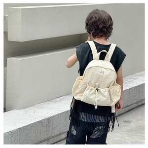 Detail of off-white nylon kids backpack showing side drawstring pocket and AN logo