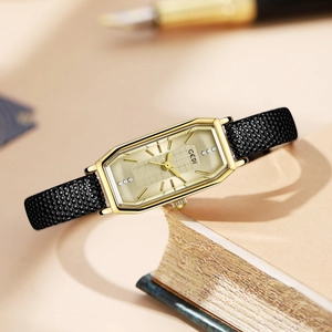 Elegant vintage square gold watch with champagne dial and black leather strap on a book
