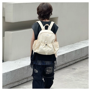 Detail of cream drawstring kids backpack with AN logo shown on a child model outdoors