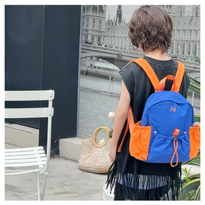 Detail of color-block kids backpack with drawstrings and AN embroidery for outdoor use