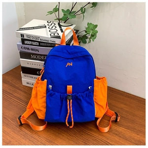 Detail of blue and orange kids backpack with drawstring front pocket and logo embroidery