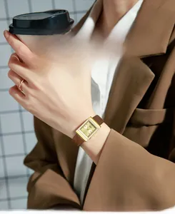 Close-up of vintage square gold watch with brown leather strap worn by a woman