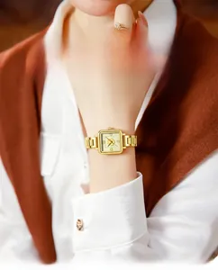 Detailed view of women's gold square watch with flower dial and solid steel strap on wrist