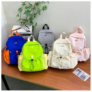 Selection of color-block nylon school backpacks in five colors displayed on a wooden table