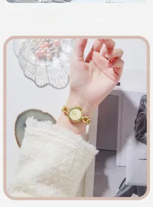Detail of gold elegant women watch featuring a round dial and stylish metal chain strap
