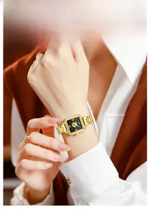 Detailed macro view of black square dial with gold floral relief and steel watch band