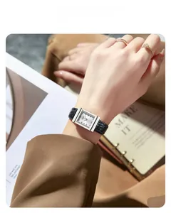 Close-up of vintage square quartz watch with black pebble grain leather strap on wrist
