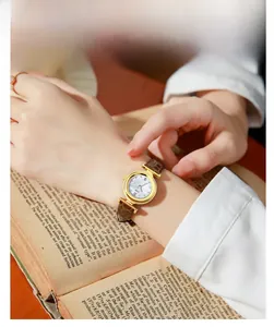 Detailed macro of a gold quartz watch with a brown leather strap on a vintage book