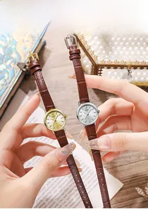 Close-up of elegant small dial watches with brown leather straps and metal cases