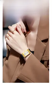 Détail d'une montre à quartz vintage dorée avec bracelet en cuir noir portée par un mannequin