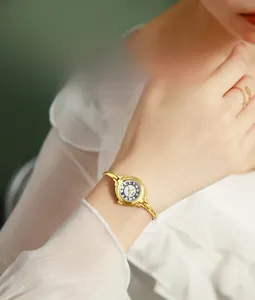 Detail of a vintage gold bangle watch with a minimalist Roman numeral dial on wrist
