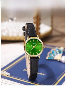 Detail view of a small green watch face with gold case and black leather strap