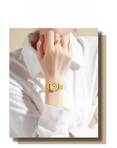 Détail d'une montre dorée à mailles et d'une bague coeur sur le poignet d'une femme