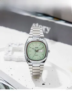 Detailed close-up of a silver stainless steel watch with a square green dial and date window