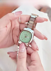 Close-up of mint green oval dial watch with dual calendar display and silver steel strap