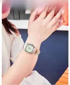 Close-up of a silver steel watch with a mint green dial and date display on a wrist