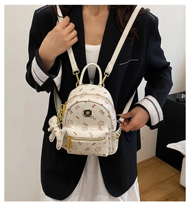 Close-up of small white PU leather backpack with bow patterns and gold logo plate