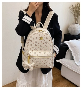 Detail of cream backpack with cat prints, side pockets, and dog charm accessory