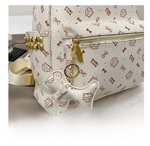 Detail of white leather backpack with cat print, gold studs and cat-shaped pendant