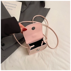 Detail of pink mini flap crossbody bag with magnetic silver clasp and black lining