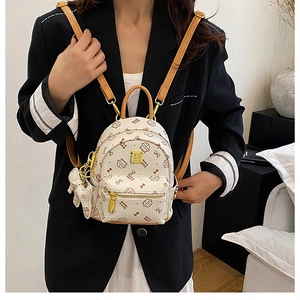 Detail of cream mini backpack featuring cartoon cat patterns and premium gold zippers
