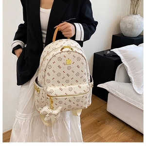 Detail of cream backpack with cat prints and cute white plush puppy charm accessory