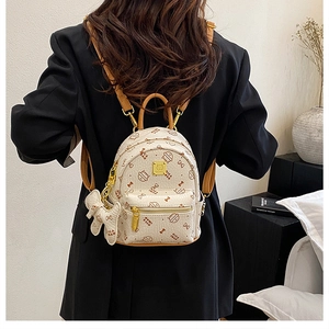 Detail of beige mini backpack with cat patterns, brown straps and golden zippers