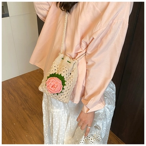 Detail der handgehäkelten Mini-Beuteltasche mit rosa 3D-Rose und Kordelzugverschluss