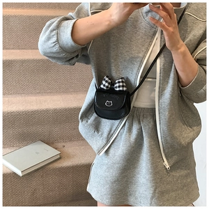 Detailed close-up of mini black crossbody bag with checkered bow and cat logo
