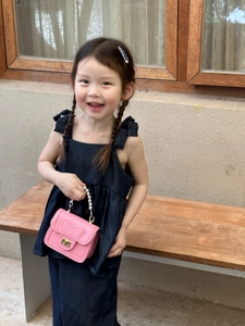 Pink girls mini bag with pearl handle and bow detail shown held by a young child