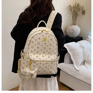 Detail of cream backpack with cat prints, side gold chain, and cute kitten charm