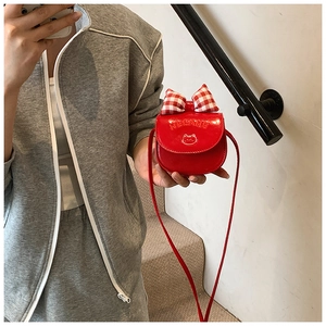 Detail of red glossy shoulder bag with plaid bow and cartoon cat print for girls