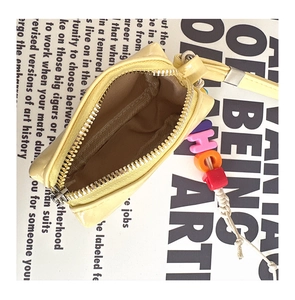 Close-up of bright yellow mini neck bag with half-moon design and internal lining