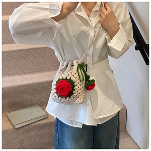 Detail der handgehäkelten Beuteltasche mit roter Rose und grünem Kordelzug-Schultergurt