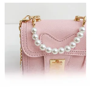 Macro detail of pink cross-grain leather mini bag with pearl handle and gold twist lock