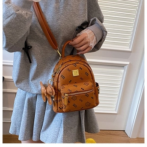 Close-up of caramel mini backpack featuring cat prints, gold zippers and bunny charm