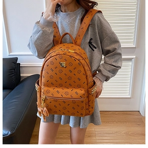 Detail of brown leather backpack with cartoon prints and metallic side chain decor