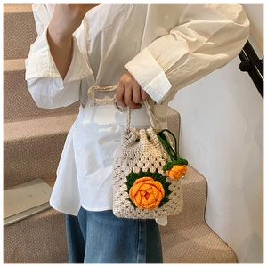 Detail der handgestrickten Beuteltasche mit orangefarbenen Häkelblumen und Kordelzug