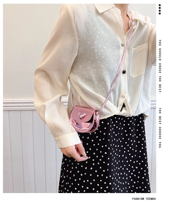 Pink metallic mini crossbody bag with embossed heart detail shown on a child model