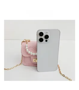 Pink mini crossbody bag for kids with pearl handle compared to iPhone for size reference