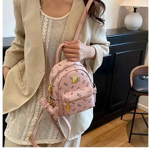 Detail of pink mini backpack with cute cat prints and gold zipper hardware on model